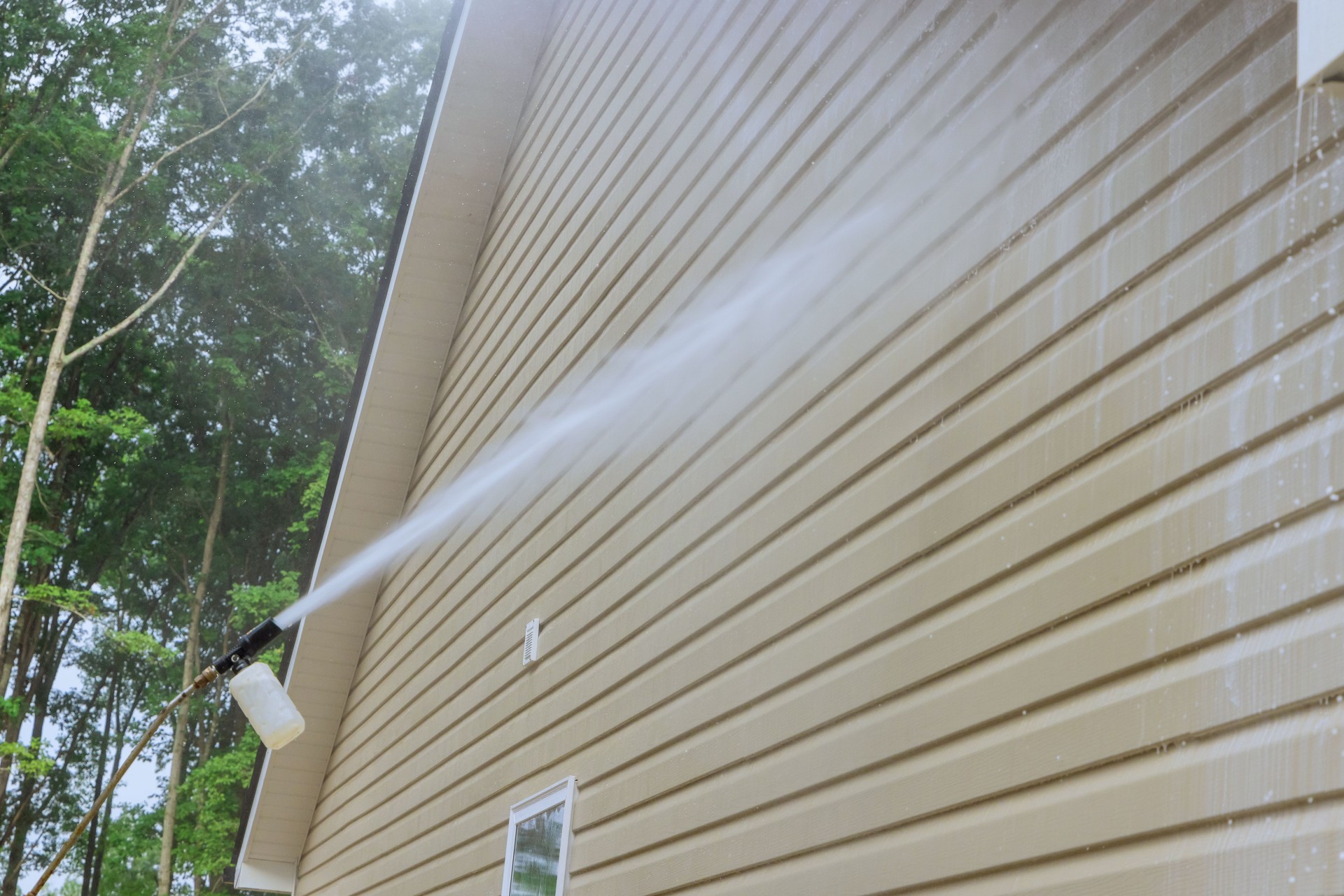 Service man in washing siding houses by using a high pressure nozzles spray water soap cleaner